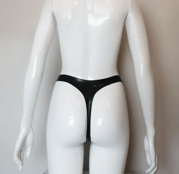 Model wearing dominant black rubber fetish harness panties showing functional removable o ring via poppers